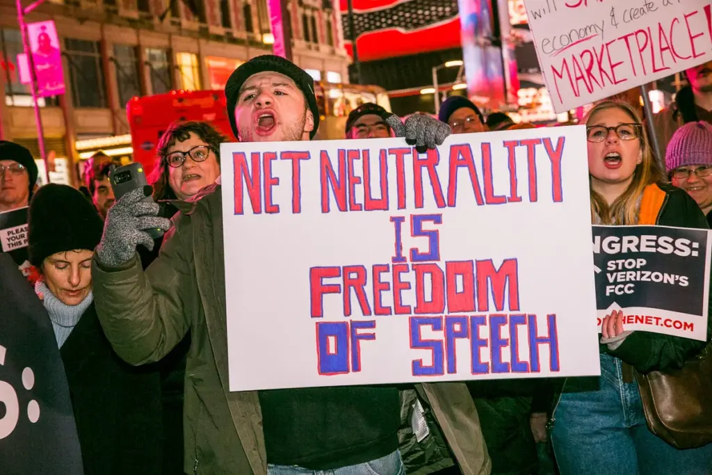 A protestor holding a sign that says "Net Neutrality is Freedom of Speech"